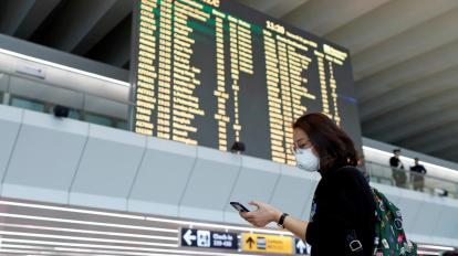 Una turista lleva una máscara de protección mientras utiliza su teléfono en el aeropuerto de Roma, en Italia.