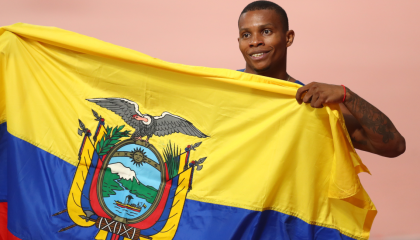 Álex Quiñónez celebra su tercer lugar en el Mundial de atletismo en Doha, con la bandera de Ecuador. 