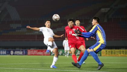 Hwang Hee-chan (blanco) de Corea del Sur, pelea una pelota ante dos jugadores del Corea del Norte. 