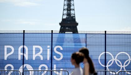 Dos mujeres pasan junto a la Torre Eiffel parcialmente oculta por una valla, antes de los Juegos Olímpicos de París, el 19 de julio de 2024.