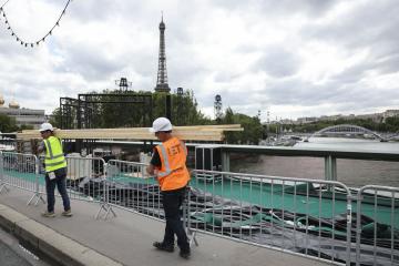 Varios operarios pasan ante el río Sena de París, este martes. El Sena será el escenario elegido para la ceremonia de inauguración de los Juegos Olímpicos el próximo viernes 26 de Julio.