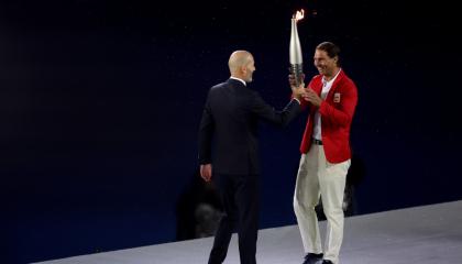 El tenista español Rafa Nadal (d) recoge la antorcha olímpica de manos del exfutbolista Zinedine Zidane en la Plaza del Trocadero durante la ceremonia de inauguración de los Juegos Olímpicos de París 2024.