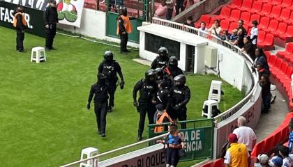 La Policía camina con el detenido por las detonaciones en el partido entre Liga de Quito y Orense, el domingo 6 de octubre de 2024.