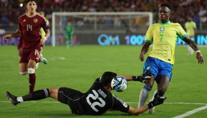 Rafael Romo (abajo) de Venezuela disputa el balón con Vinícius Júnior de Brasil, este jueves 14 de noviembre, durante la Fecha 11 de las Eliminatorias al Mundial 2026.