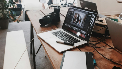 Fotografía referencial de distintos dispositivos tecnológicos como laptops, cámaras y tabletas graficadoras en una mesa.