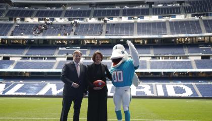 Brett Gosper, director de la NFL en Europa y Asia-Pacífico y Pri Shumate, vicepresidenta de los Miami Dolphins, en el césped del estadio Santiago Bernabéu con la mascota del equipo, durante el acto celebrado este viernes 17 de enero en Madrid en el que la NFL, la Liga profesional de fútbol americano, ha anunciado que los Miami Dolphins serán el 'equipo designado' (local) en el partido de ese campeonato que se disputará este año en el mencionado estadio de la capital.