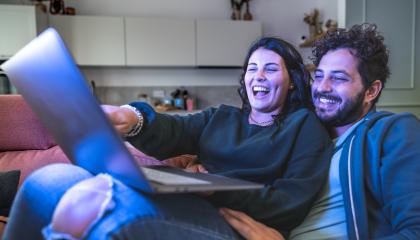 Pareja observa contenido en una laptop mientras comparte un momento en casa.