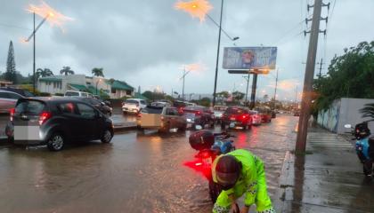 Un agente de la ATM despeja una alcantarilla tapada en una avenida inundada, norte de Guayaquil, el 19 de octubre de 2026.