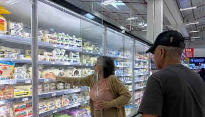 Consumidores en la sección lácteos de un supermercado.