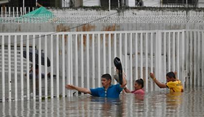 Personas caminan con el agua al pecho durante las lluvias torrenciales en el norte de Guayaquil, tras la tormenta del 26 de octubre de 2026 que colapsó gran parte de Guayaquil.