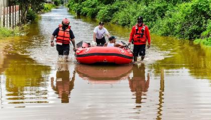 Bomberos de Machala evacúan a un adulto mayor por las inundaciones en la zona norte de la ciudad, el 27 de octubre de 2026.