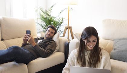 Imagen referencial de dos personas que utilizan distintos dispositivos para conectarse desde su hogar.