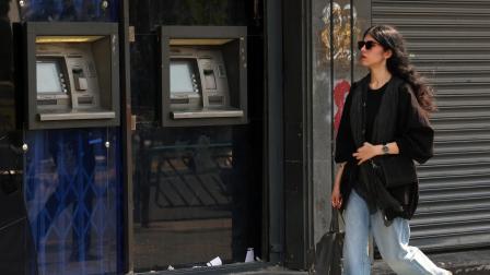 Mujer camina frente a un banco en Teherán, Irán, el 13 de agosto de 2026.