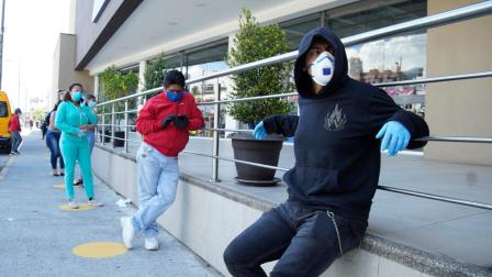 Ciudadanos hacen fila en los exteriores de un supermercado de Quito que ha pintado marcas en el piso para mantener el distanciamiento entre clientes, el 24 de abril de 2020.