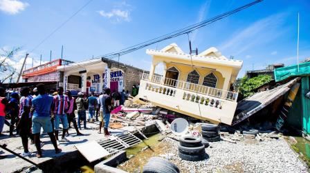 Varias personas permanecen junto a los escombros de una casa en Haití, el 15 de agosto de 2021.