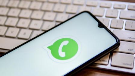 Un teléfono inteligente con el logo de WhatsApp, sobre un teclado. 