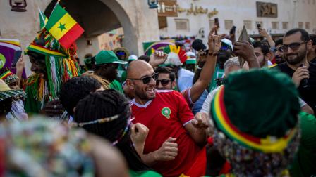 Un hincha de Marruecos baila con los fanáticos de Senegal en el mercado tradicional Souq Waqif, el 1 de diciembre de 2022.