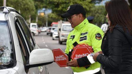 Un agente de tránsito  de Cuenca da información a un conductor sobre una campaña de educación vial.