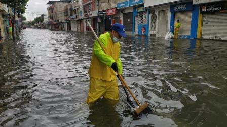 Un trabajador de Urvaseo recoge desechos en medio de la inundación de un sector de la ciudela Sauces 6, al norte de Guayaquil, la mañana del 11 de febrero de 2025.