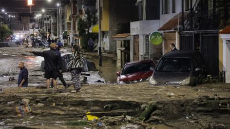 Varias personas observan junto a coches y casas afectadas por las fuertes lluvias en el distrito de Yanahuara, en Arequipa, 19 de febrero de 2026.