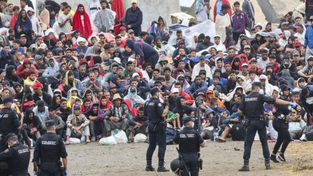 La policía vigila a inmigrantes que continúan viviendo en las inmediaciones de la playa del Trampolín en Ceuta, territorio español en el norte de África, el 21 de agosto de 2026.
