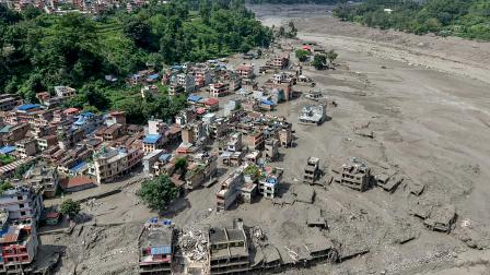 Varias casas permanecen parcialmente sumergidas en aguas turbias a orillas de un río tras unas inundaciones repentinas en Trishuli Bazar, en el distrito nepalí de Nuwakot, el 26 de agosto de 2026.