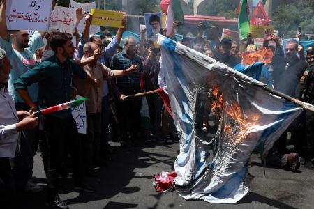 Iraníes queman una bandera de Israel en una manifestación en Teherán, tras nuevo bombardeos israelíes, el 20 de junio de 2025.