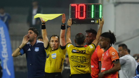 Árbitros ecuatorianos levantan el cartel electrónico y alzan la bandera durante el partido entre Emelec y Libertad, en Guayaquil, el 19 de septiembre de 2026.