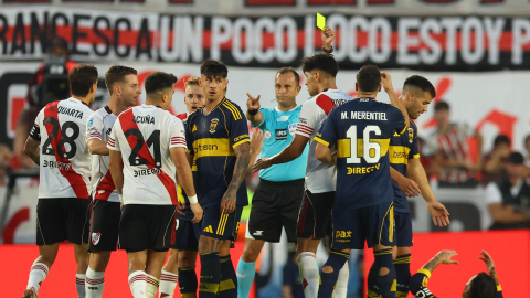 El árbitro argentino Darío Herrera muestra una tarjeta amarilla al defensa, Marcos Acuña, durante el partido entre River Plate y Boca Juniors, en el estadio MAS Monumental, el 19 de abril de 2026.