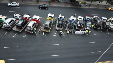 Agentes de la Agencia Nacional de Tránsito junto a las grúas y algunos de los vehículos retenidos por circular sin placas.