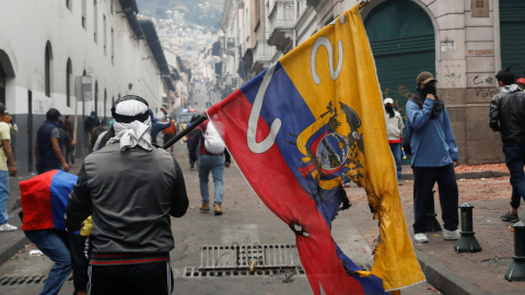 Un manifestante extiende una bandera maltratada de Ecuador.