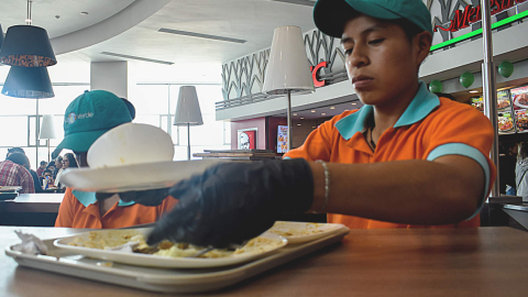 Un trabajador recoge platos ecológicos de la empresa Huella Verde en un patio de comidas.