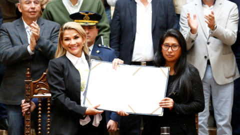 Jeanine Añez, presidenta interina de Bolivia, sostiene la ley para las nuevas elecciones junto con Eva Copa, presidenta del Senado..