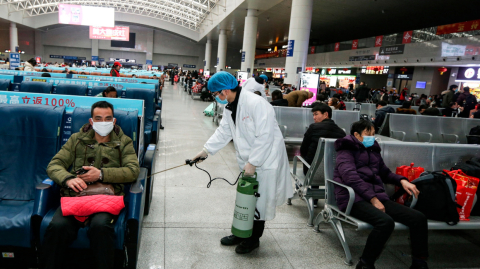 Un operario desinfecta una zona de espera para pasajeros en la estación de tren en China