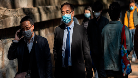 Empleados usando mascarillas se dirigen a sus trabajos en Hong Kong, donde se reporta un fallecido por el coronavirus. 