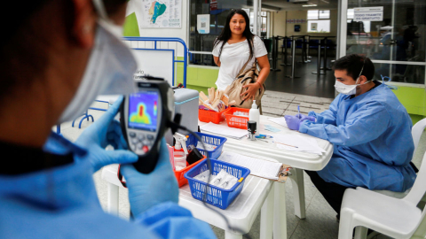 Personal del Ministerio de Salud revisa a personas en el puente de Rumichaca, norte de Ecuador, tras el brote de coronavirus en el país. 