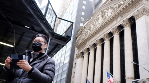 Un hombre, afuera del mercado de valores de Nueva York, usa una mascarilla para protegerse del coronavirus.