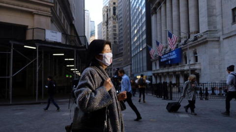 Una mujer camina en Wall Street, en Nueva York, protegida con una mascarilla.