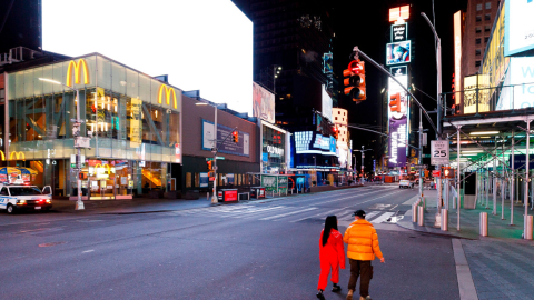 Dos personas caminan en el Times Square de Nueva York, ciudad donde solo están abiertos locales de productos esenciales desde el pasado 20 de marzo. 