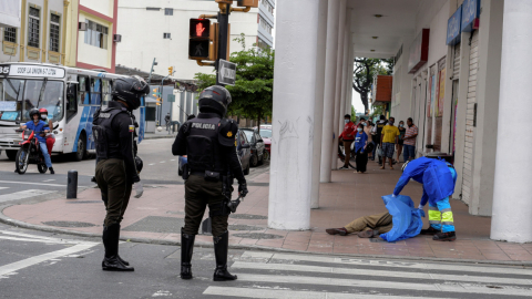 Agentes de la Policía retiran el cuerpo de un fallecido en el centro de Guayaquil, el 31 de marzo. 