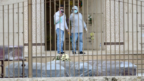 Dos hombres observan una féretros en el cementerio Parques de Esperanza, en Guayaquil, el 1 de abril de 2020.