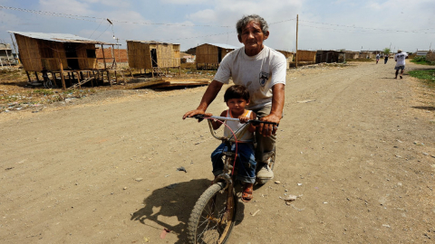 Un adulto mayor y un niño pasean en bicicleta en la zona de Ciudad de Dios en Guayaquil, el 3 de abril de 2020.