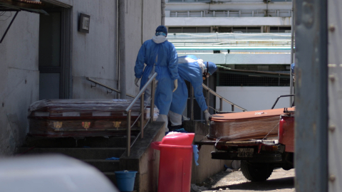 Trabajadores del hospital Teodoro Maldonado Carbo Hospital, en Guayaquil, cargan los ataúdes de dos personas fallecidas por coronavirus, el 3 de abril de 2020.