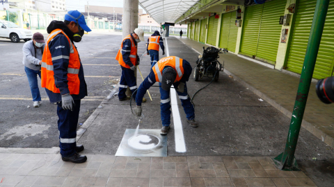 Personal de la Epmmop señaliza el mercado de Iñaquito, en el norte de Quito, para garantizar el distanciamiento social, el 8 de abril. 