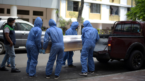 Trabajadores de una funeraria cargan el ataúd de un hombre que haría fallecido por coronavirus el 8 de abril de 2020.