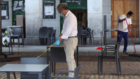 Un camarero comprueba la distancia entre mesas en la terraza de su bar de la Plaza Mayor en Madrid, 25 de mayo de 2020.