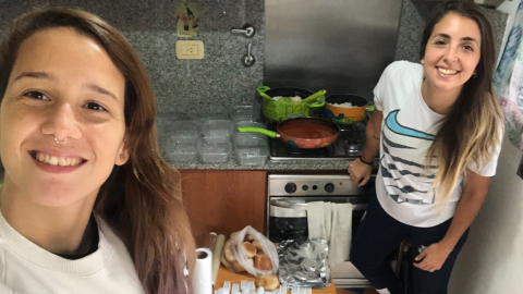 Daiana Leguizamón (d) con su pareja Carolina Teisseire (i), mientras cocinan para personas sin hogar en Buenos Aires.