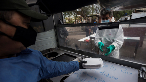 Personas preparan almuerzos, el martes 30 de junio, para ayudar a familias afectadas por la pandemia de la Covid-19 en la comuna de Conchalí en Santiago. 