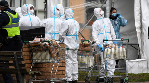 Bomberos vistiendo trajes de bioseguridad reparten comida en un barrio de Melbourne, Australia, el 7 de julio. 