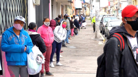 Personas realizan fila mientras esperan un bus en Calderón, el 3 de junio de 2020.